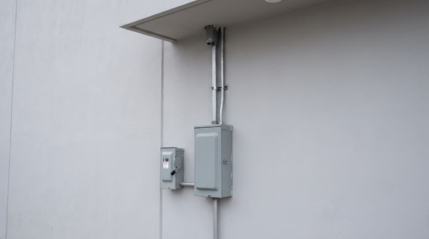Acometida eléctrica exterior con gabinete de medición, tubería y mufa en la fachada de un edificio